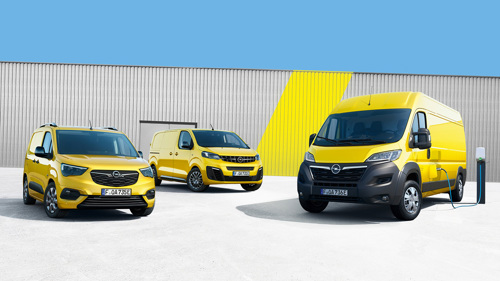 Tre gula Opel transportbilar står parkerade framför en lagerlokal